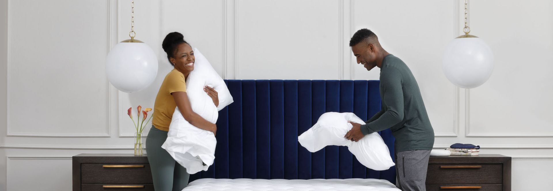 Couple holding pillows over bed