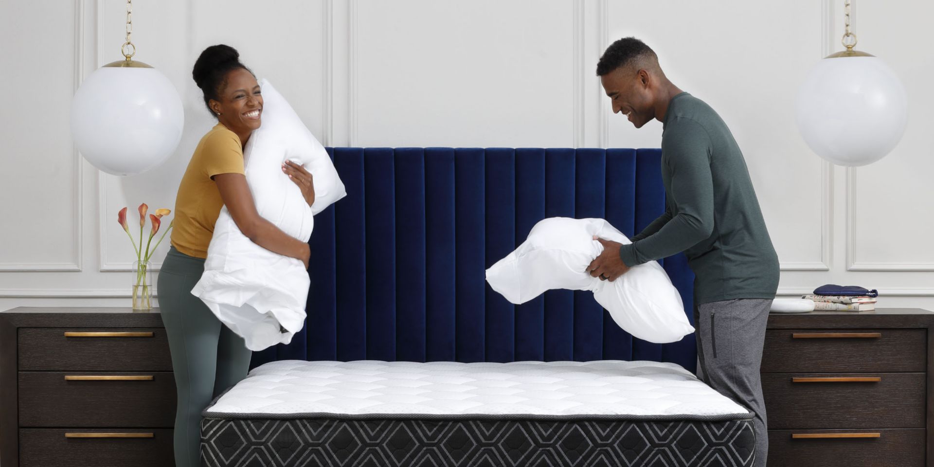 Couple holding pillows over bed