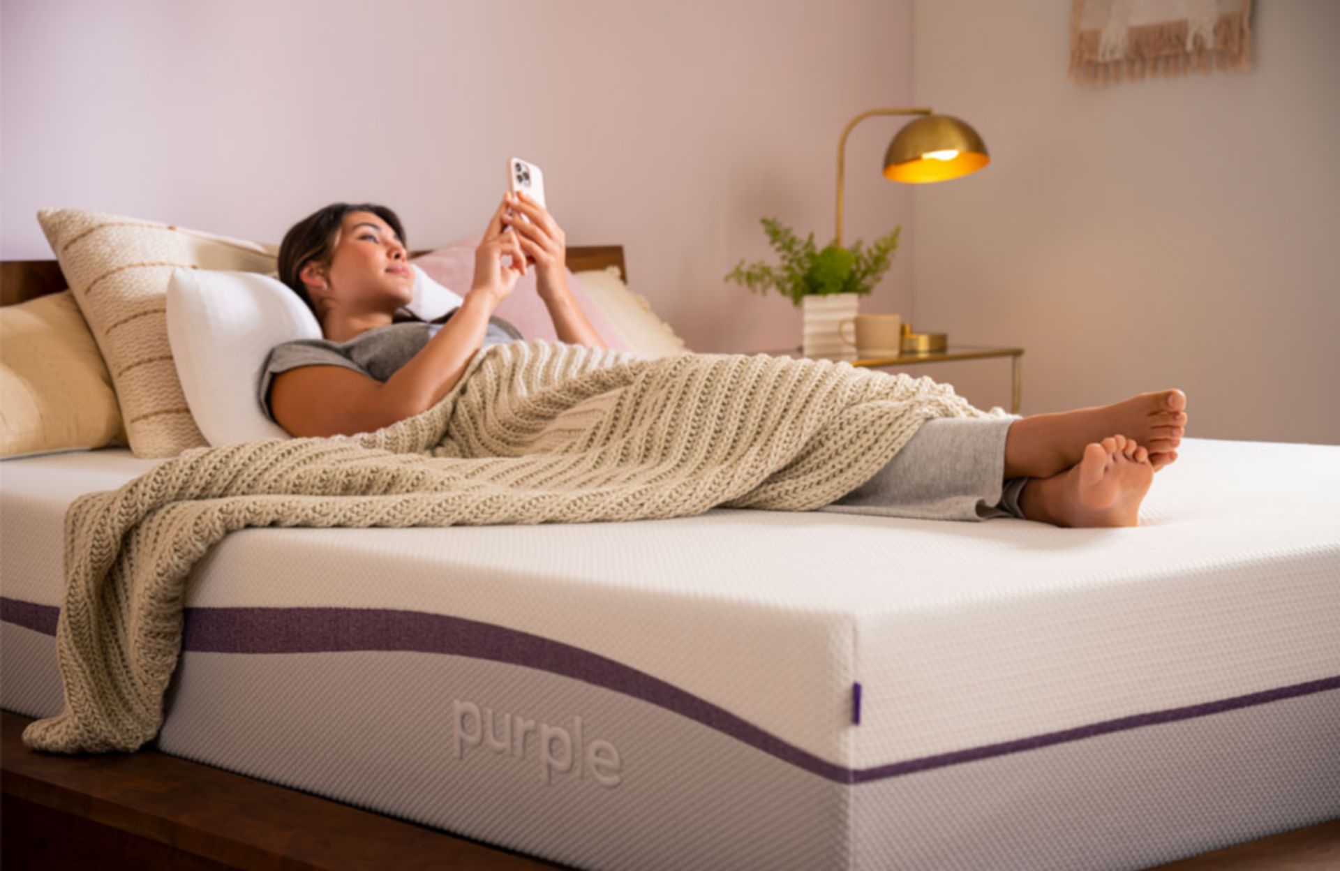 Woman Laying on Purple Mattress with Blanket looking at phone