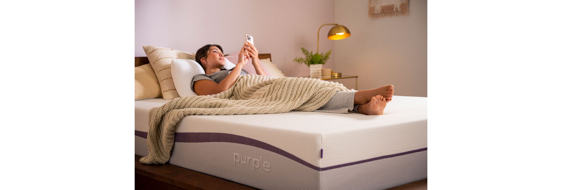 Woman Laying on Purple Mattress with Blanket looking at phone