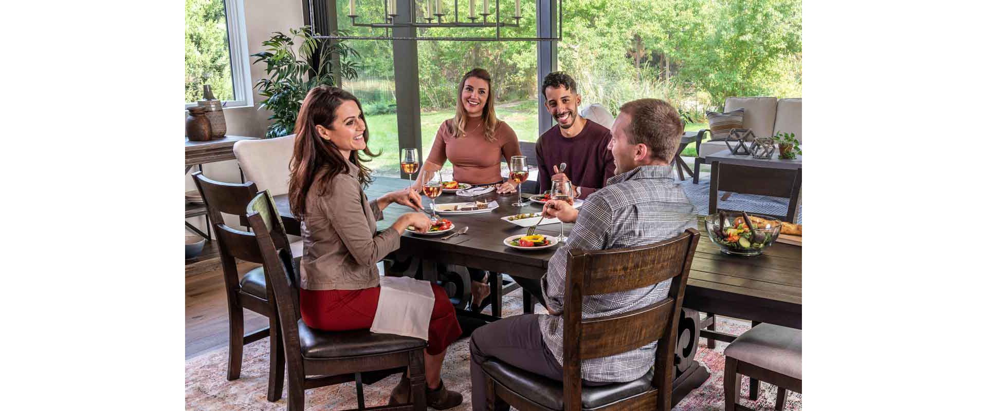 four friends sitting and eating together around the Sedona Dining Table